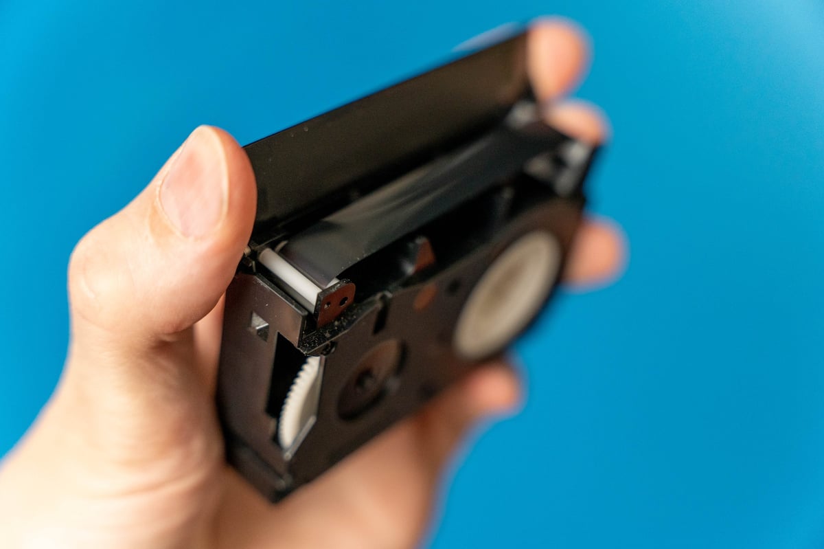 Person holding a VHS video cassette tape with blue background